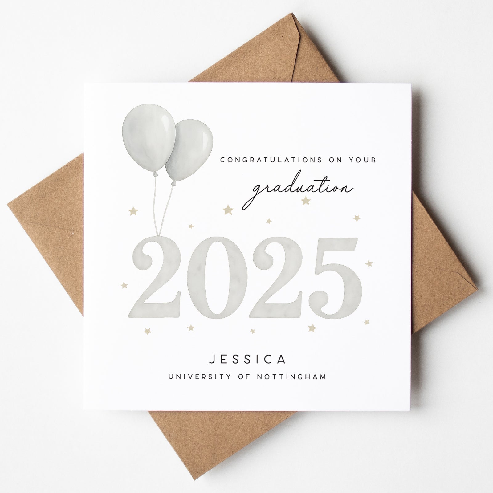 Personalised graduation card featuring soft grey balloons, gold stars, and bold “2025” lettering. Includes the name “Jessica” and “University of Nottingham.” Paired with kraft brown envelope.