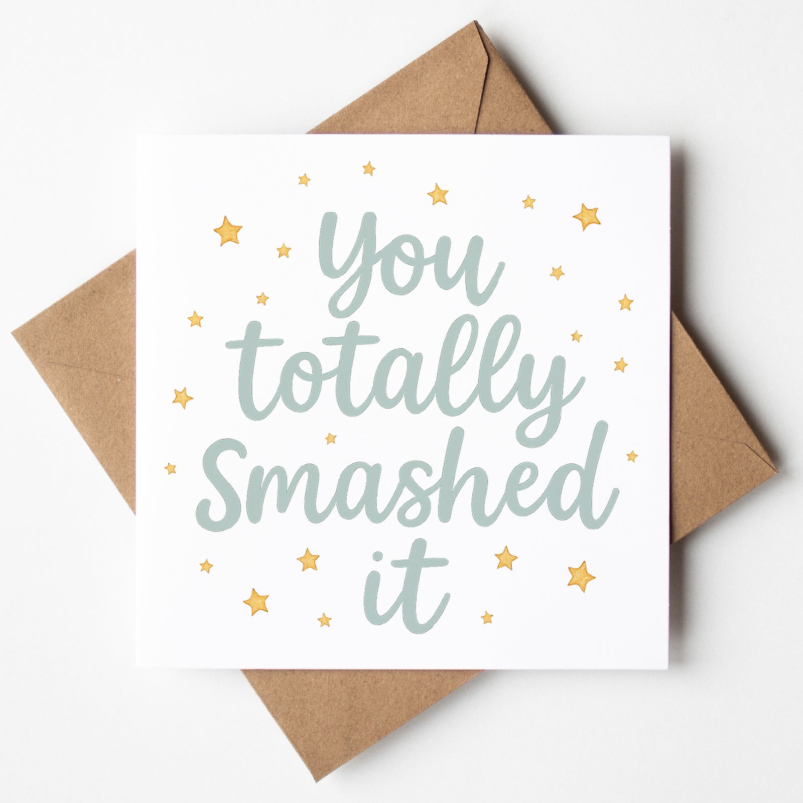 Graduation card with the phrase “You totally smashed it” in bold script, surrounded by gold stars. A celebratory design shown with a kraft brown envelope.