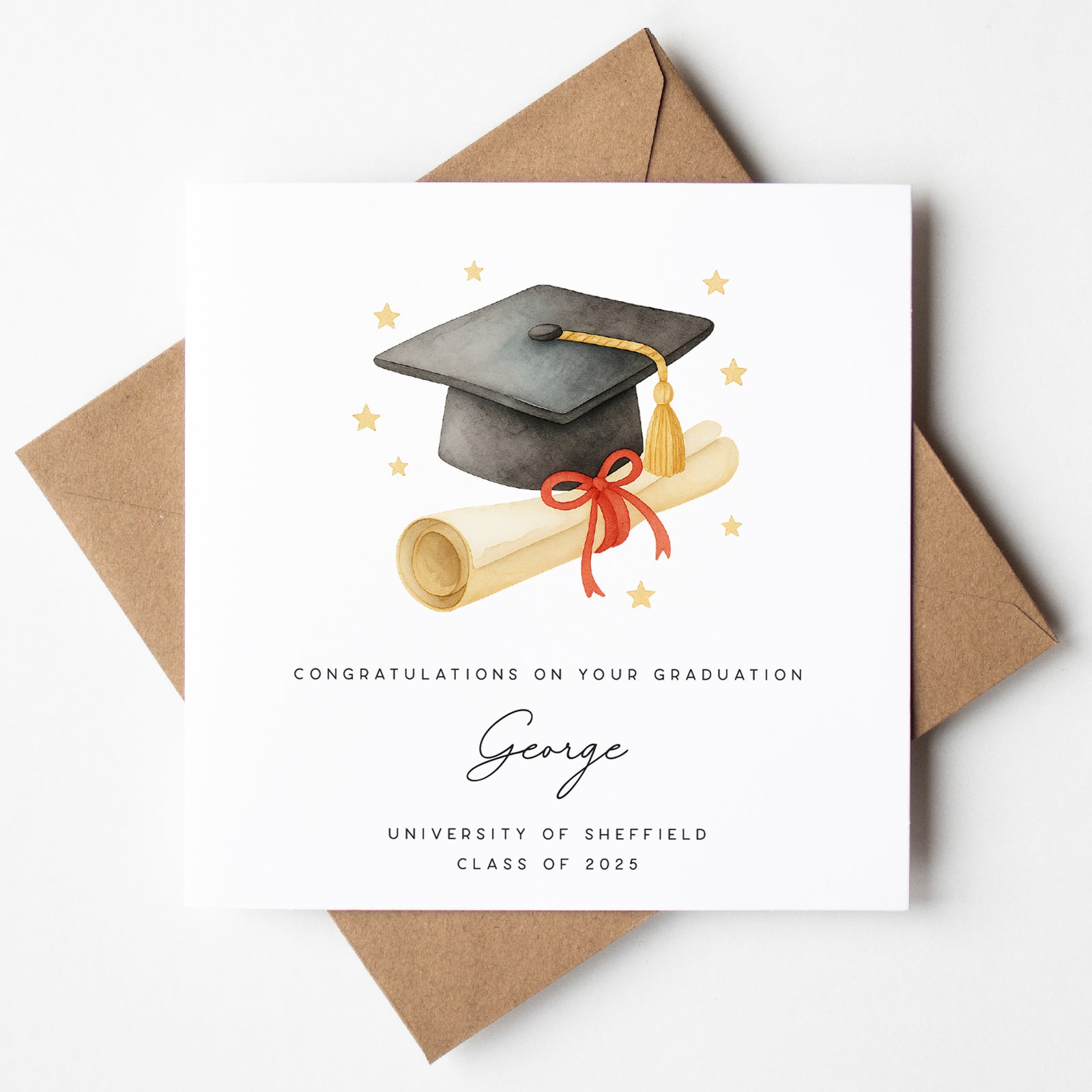 Personalised graduation card featuring a black mortarboard with gold tassel, rolled diploma tied with a red ribbon, and gold stars. Includes the name “George,” “University of Sheffield,” and “Class of 2025.” Shown with kraft brown envelope.