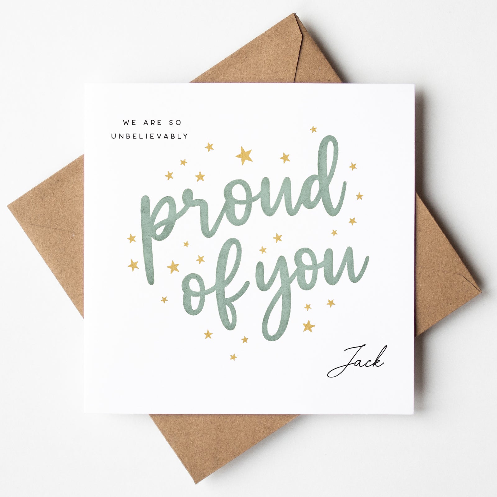 Personalised graduation card with green script text reading “Proud of You,” surrounded by gold stars. Features custom name “Jack” and kraft brown envelope.