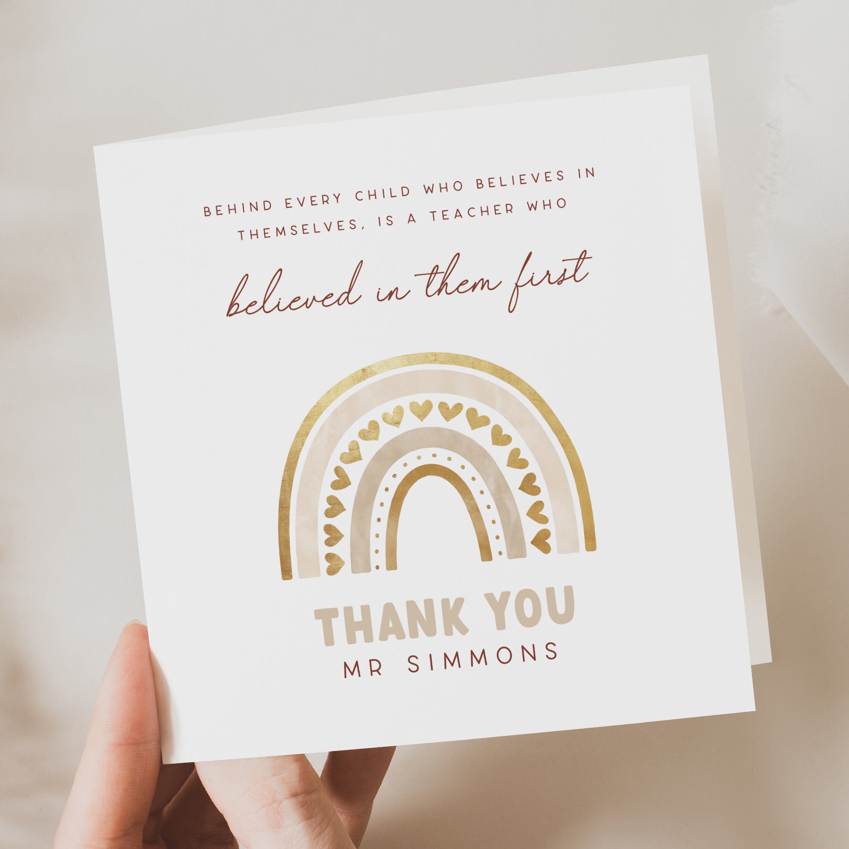 Personalised thank you card featuring a gold rainbow with hearts and the quote: “Behind every child who believes in themselves is a teacher who believed in them first.” Customised with “Mr Simmons.”