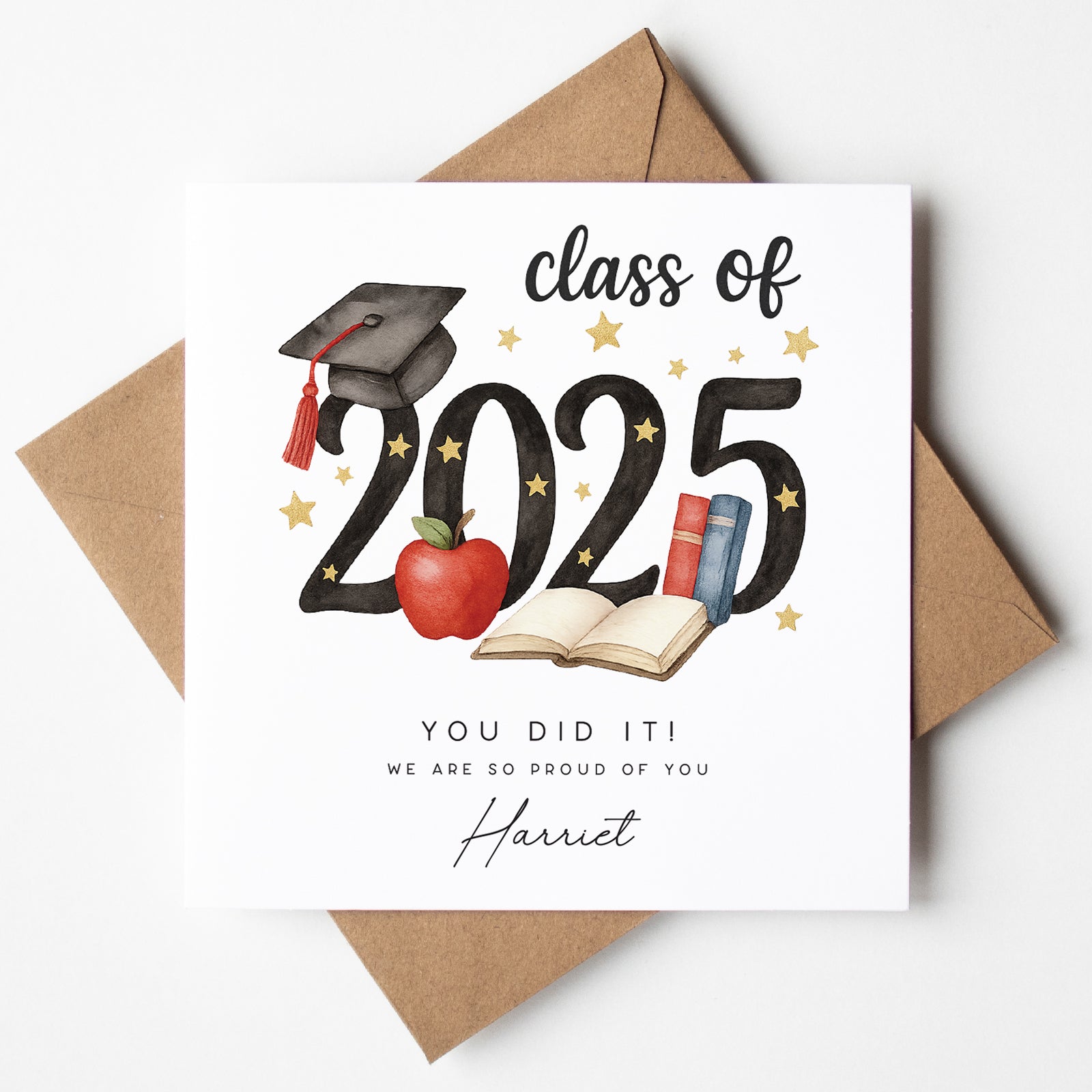 Personalised Class of 2025 graduation card featuring a black mortarboard with red tassel, red apple, open book, and stars. Custom text reads "You did it!" and includes the graduate’s name “Harriet.” Card is paired with a brown kraft envelope.